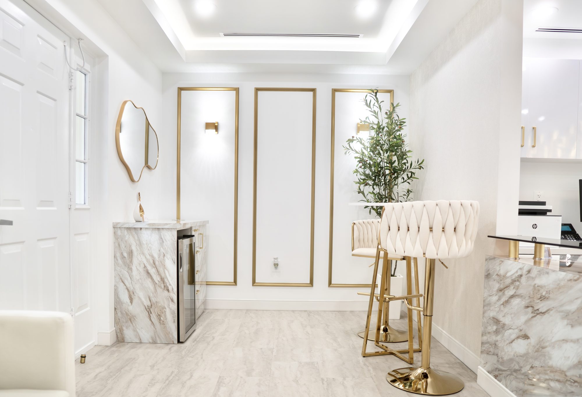 The lounge at Dr. Nahlah's Alexandria office, with a marble counter, gold-trimmed panels and bar stools