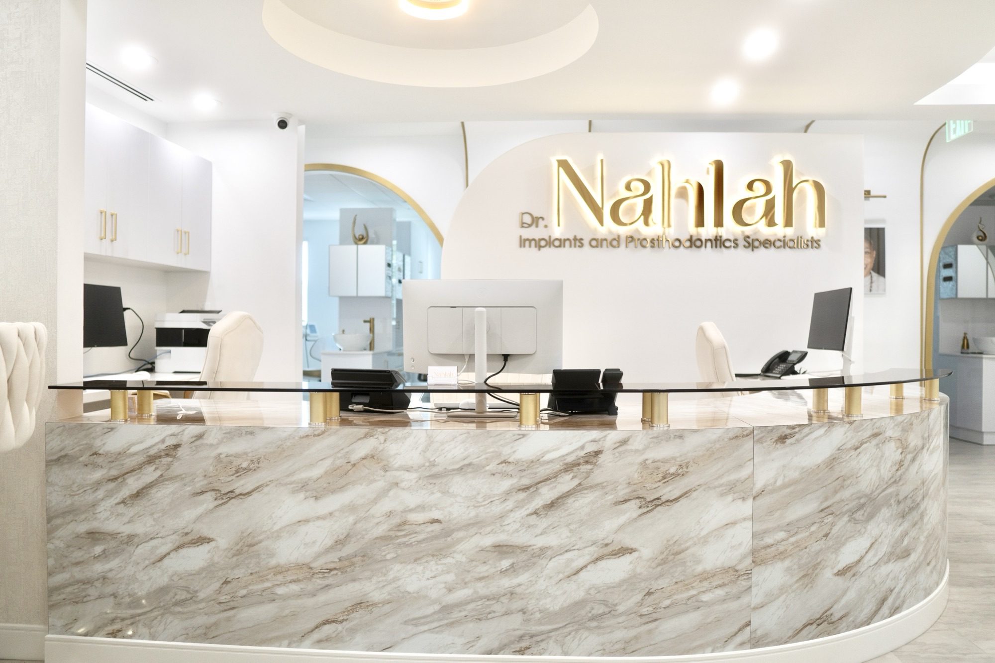 Reception at Dr. Nahlah's Alexandria office, the gold Dr. Nahlah sign above a curved marble counter