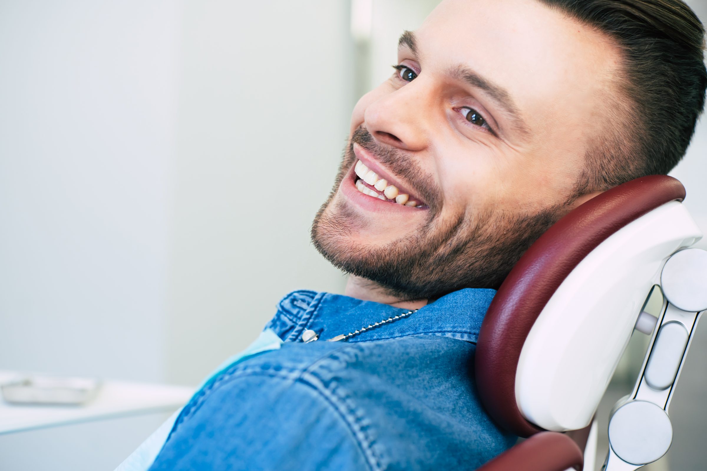 Smiling man reclining in a dental chair, looking relaxed and confident about his teeth