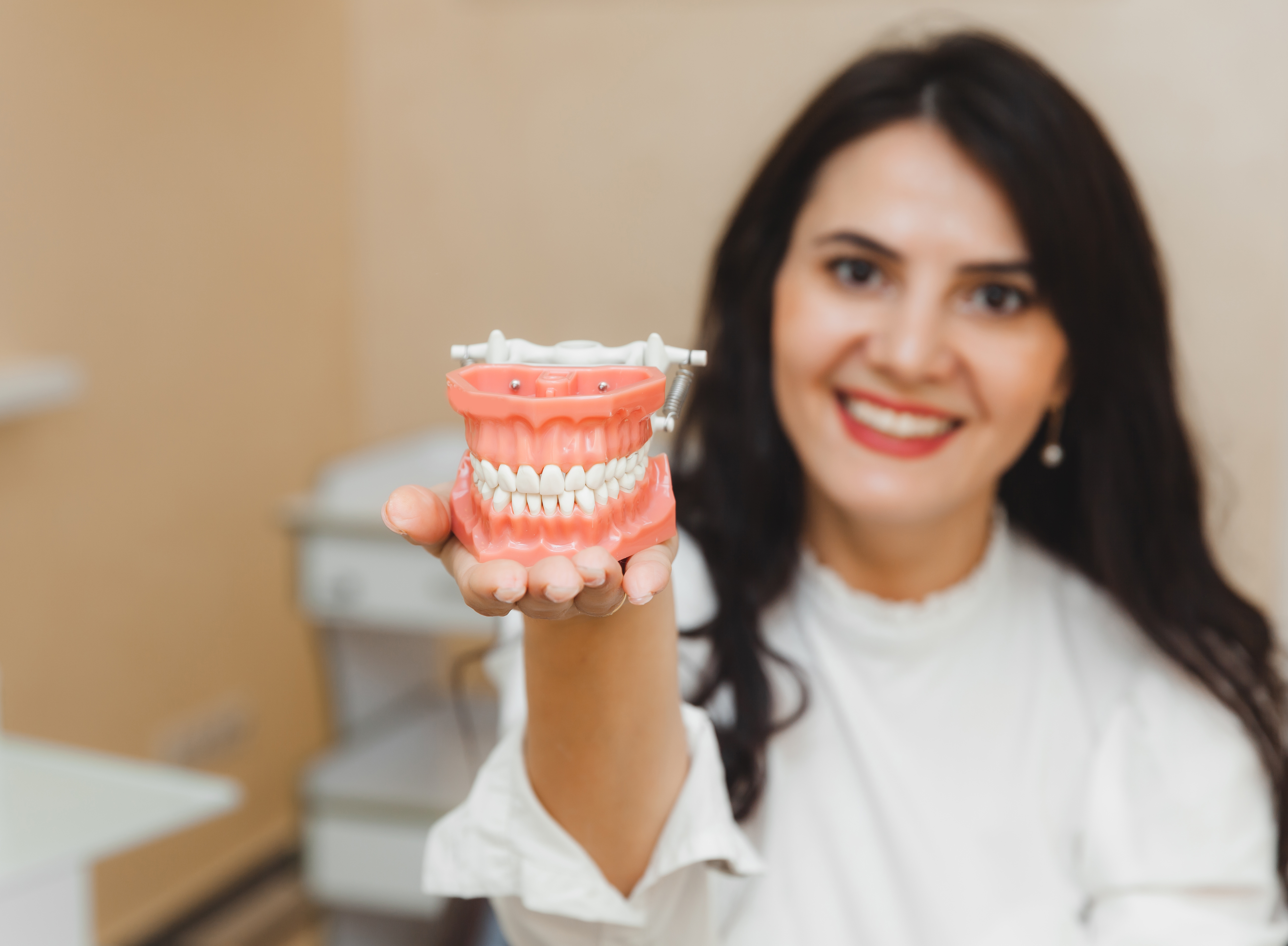 Woman holding a tooth sample or denture at the dentist medicine and dentistry concept
