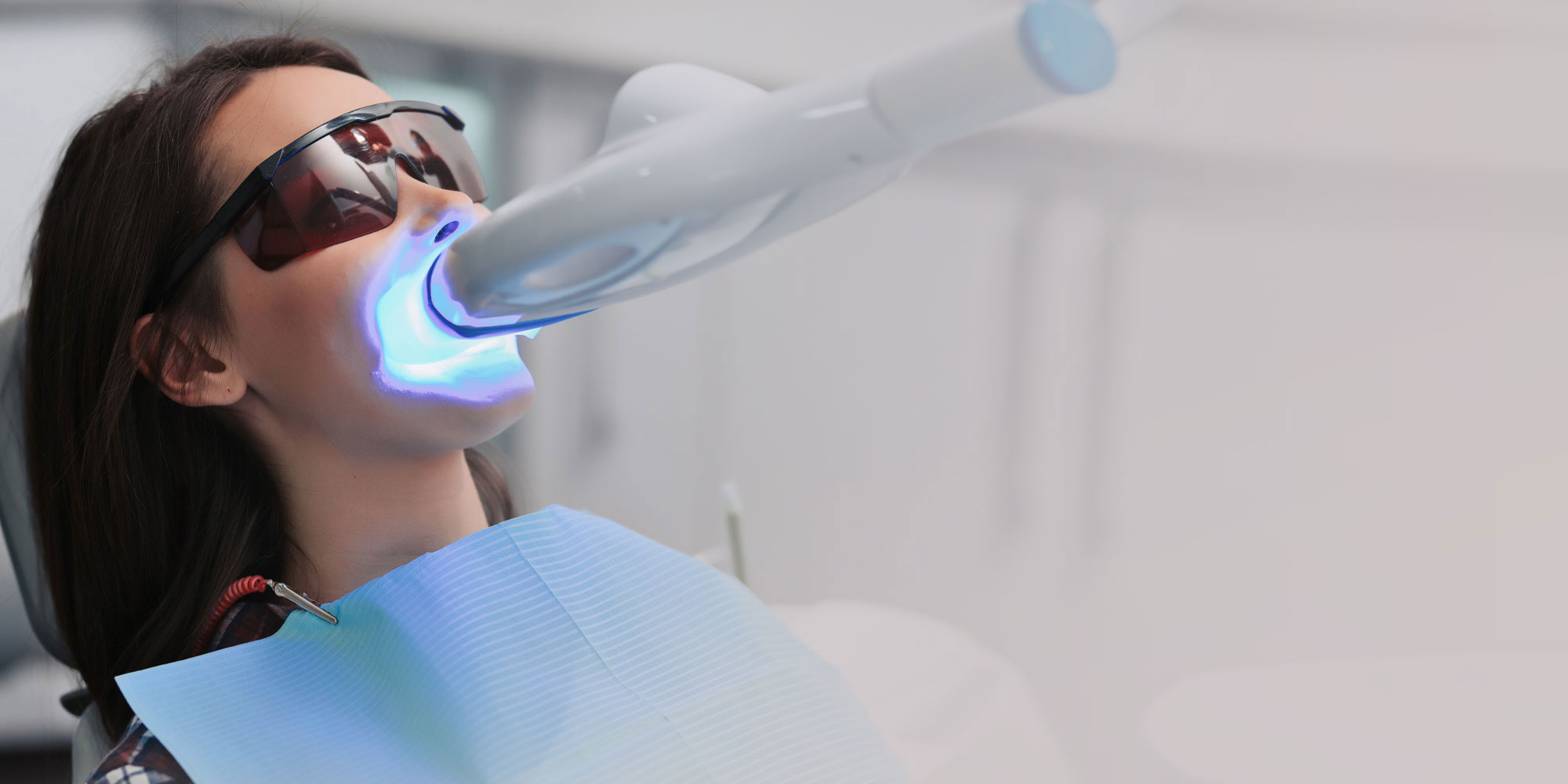 In-office whitening under a blue LED light, the patient in protective eyewear