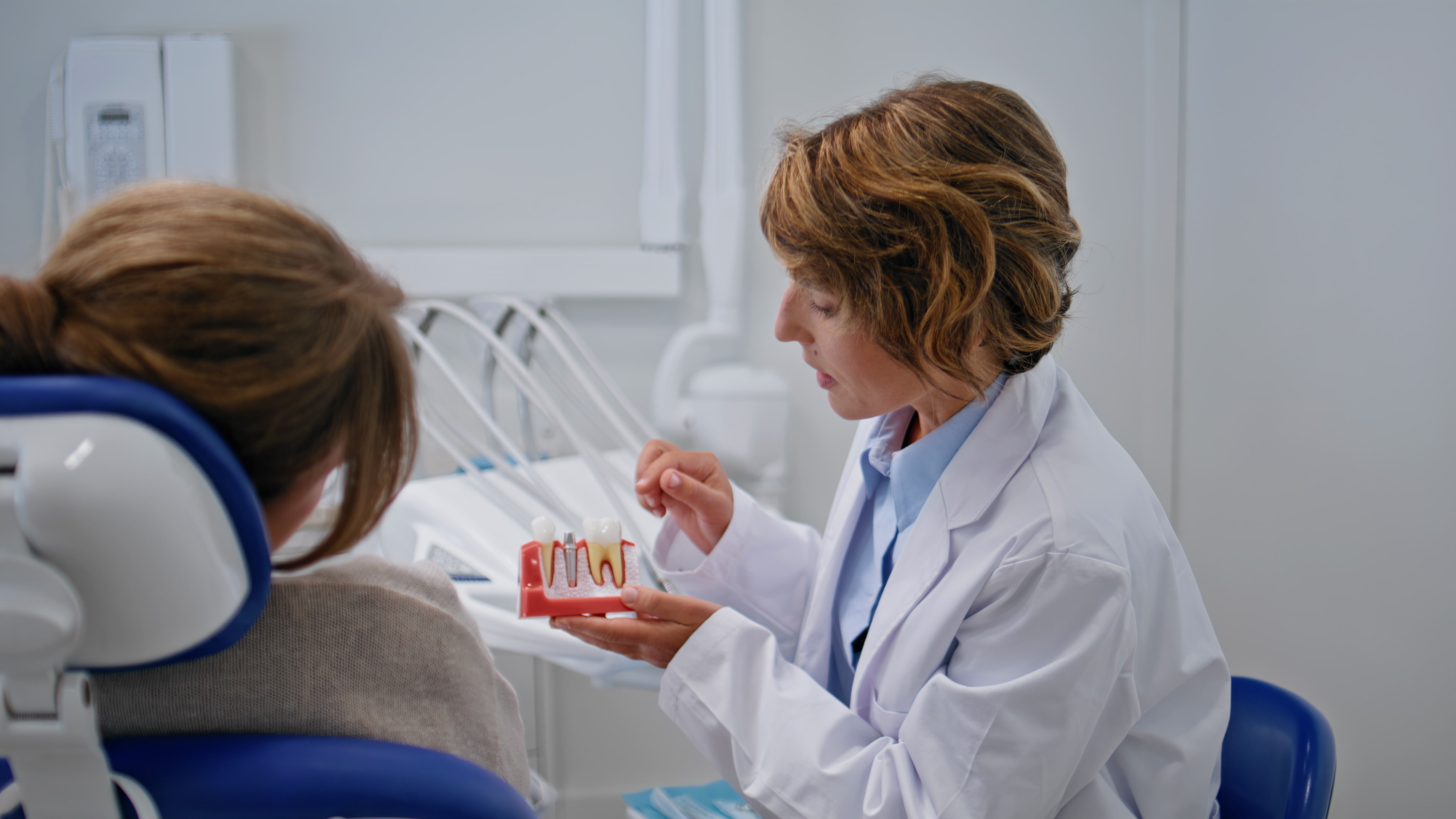 A dentist explaining an implant procedure to a patient in the clinic