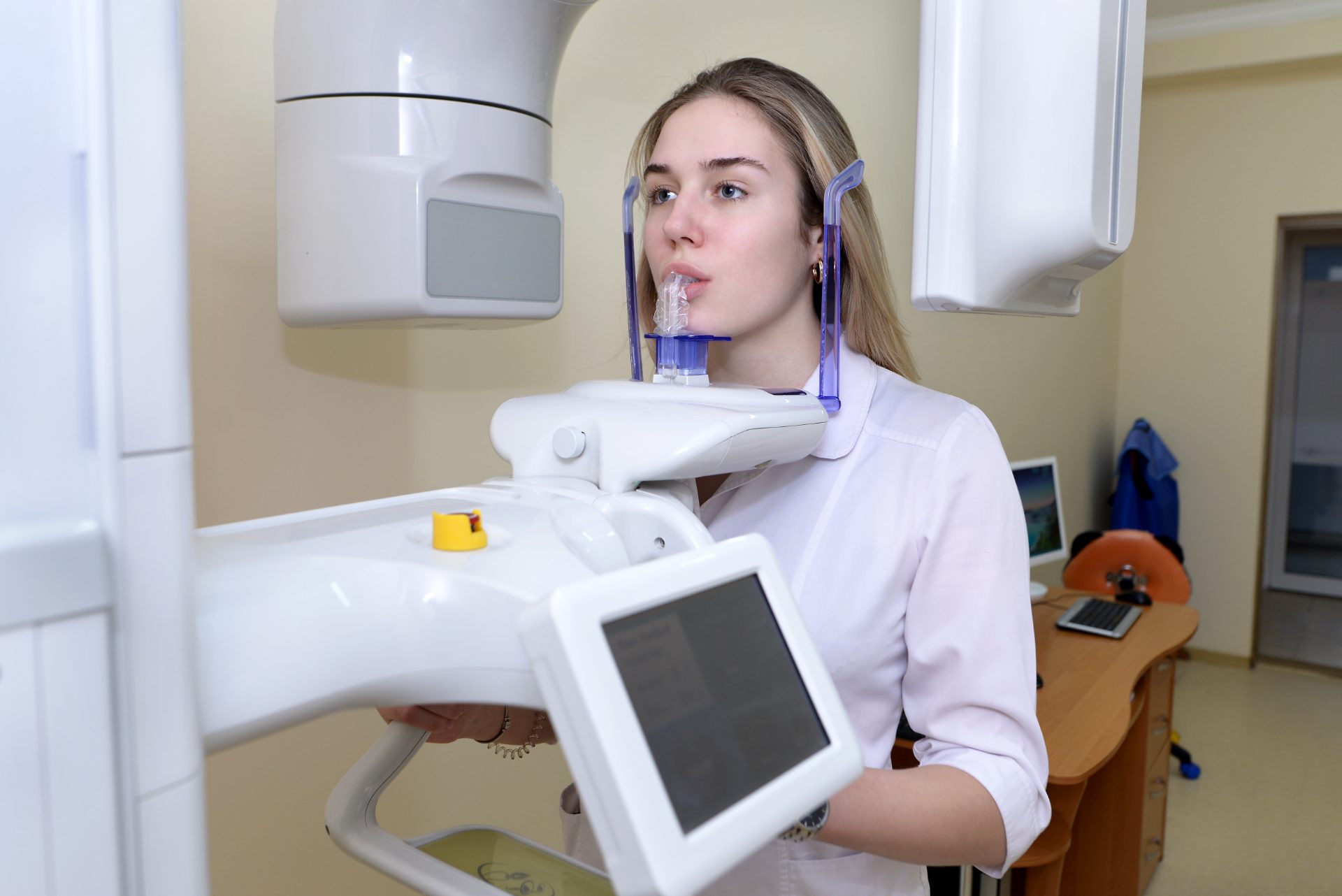 A person standing in a panoramic X-ray and cone-beam scanner, chin on the rest