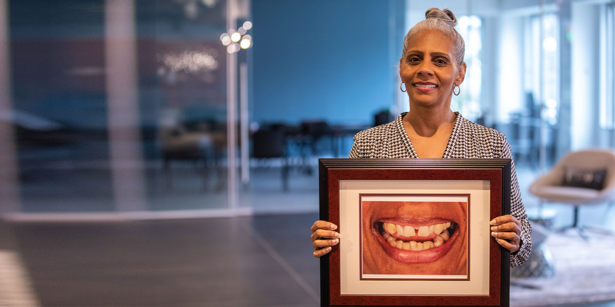 A patient holding a framed close-up photograph of her smile before treatment