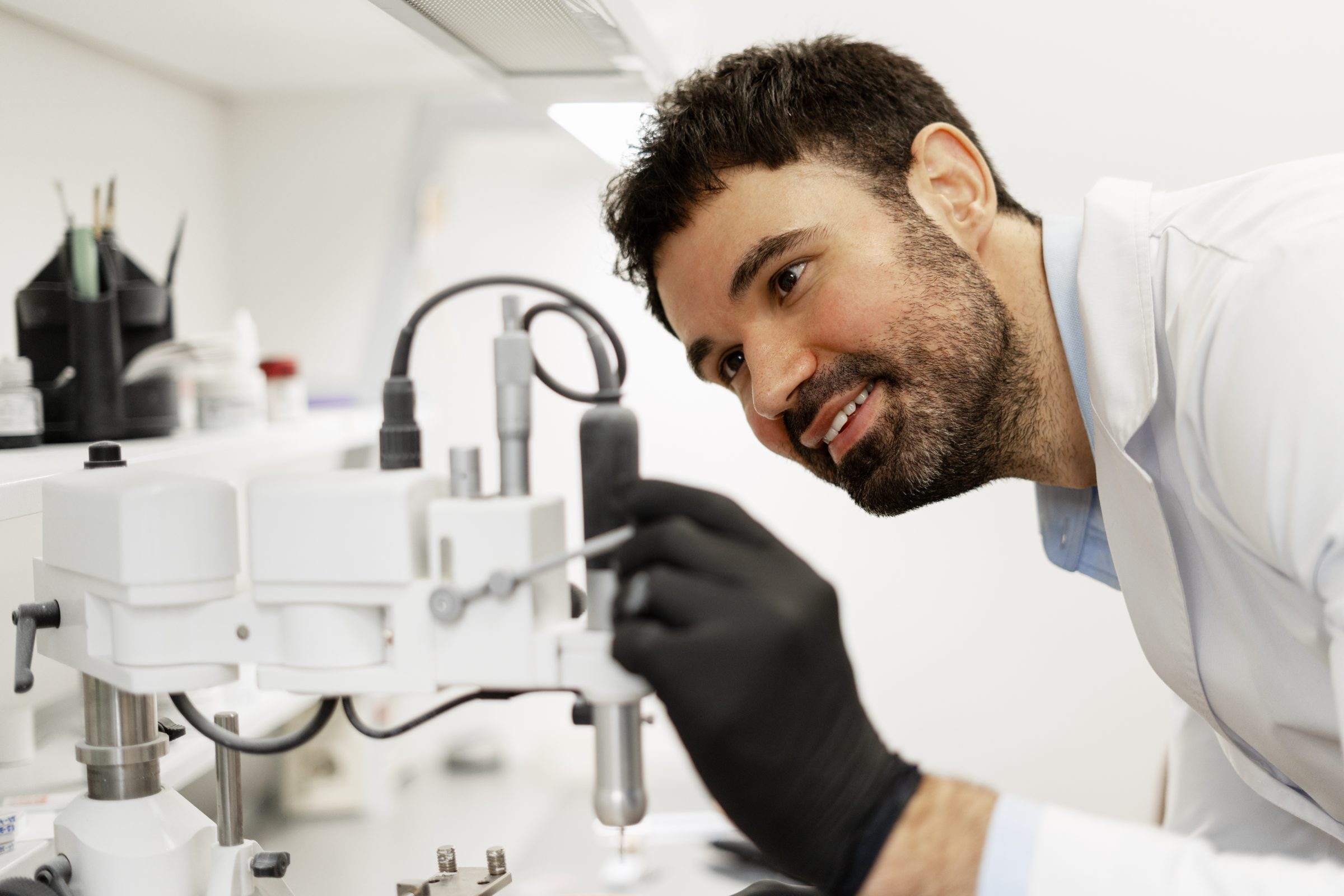 Dental technician in black gloves working at a precision milling instrument in a dental lab