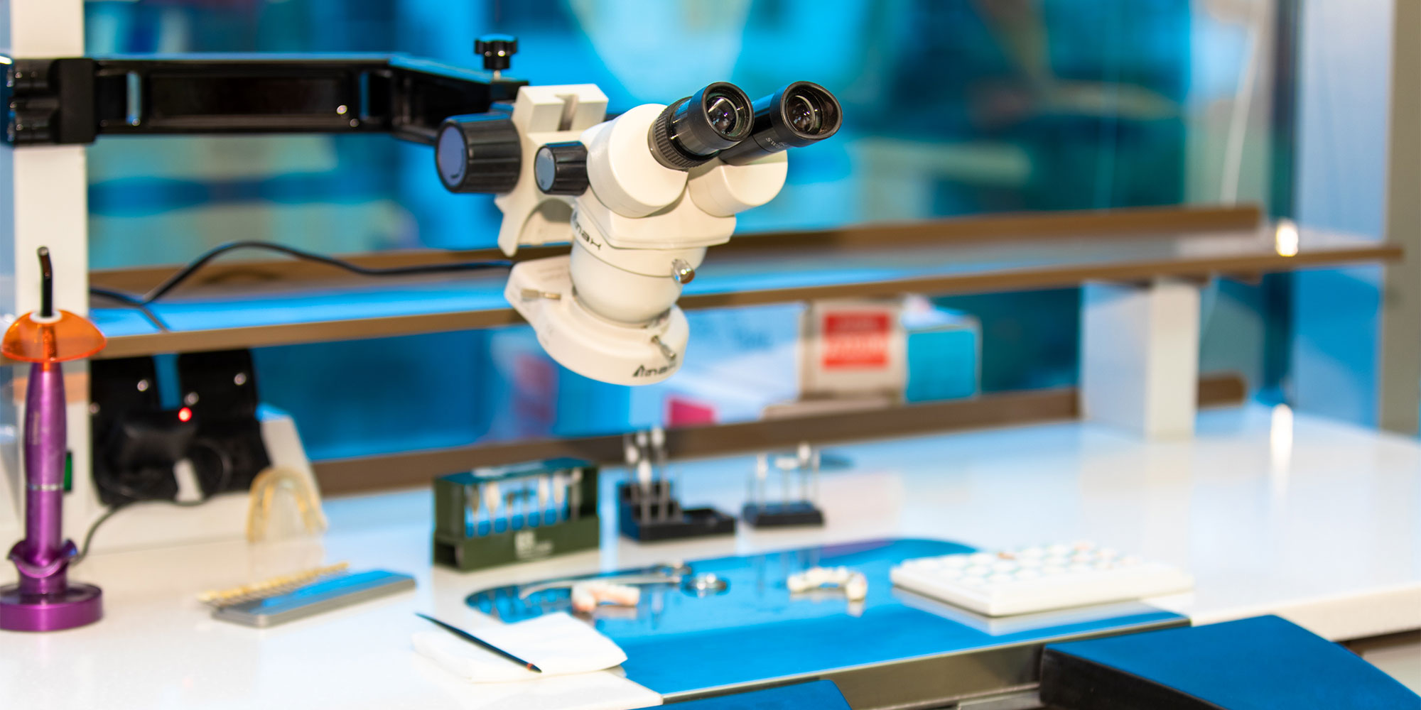 A stereo microscope over a dental laboratory bench
