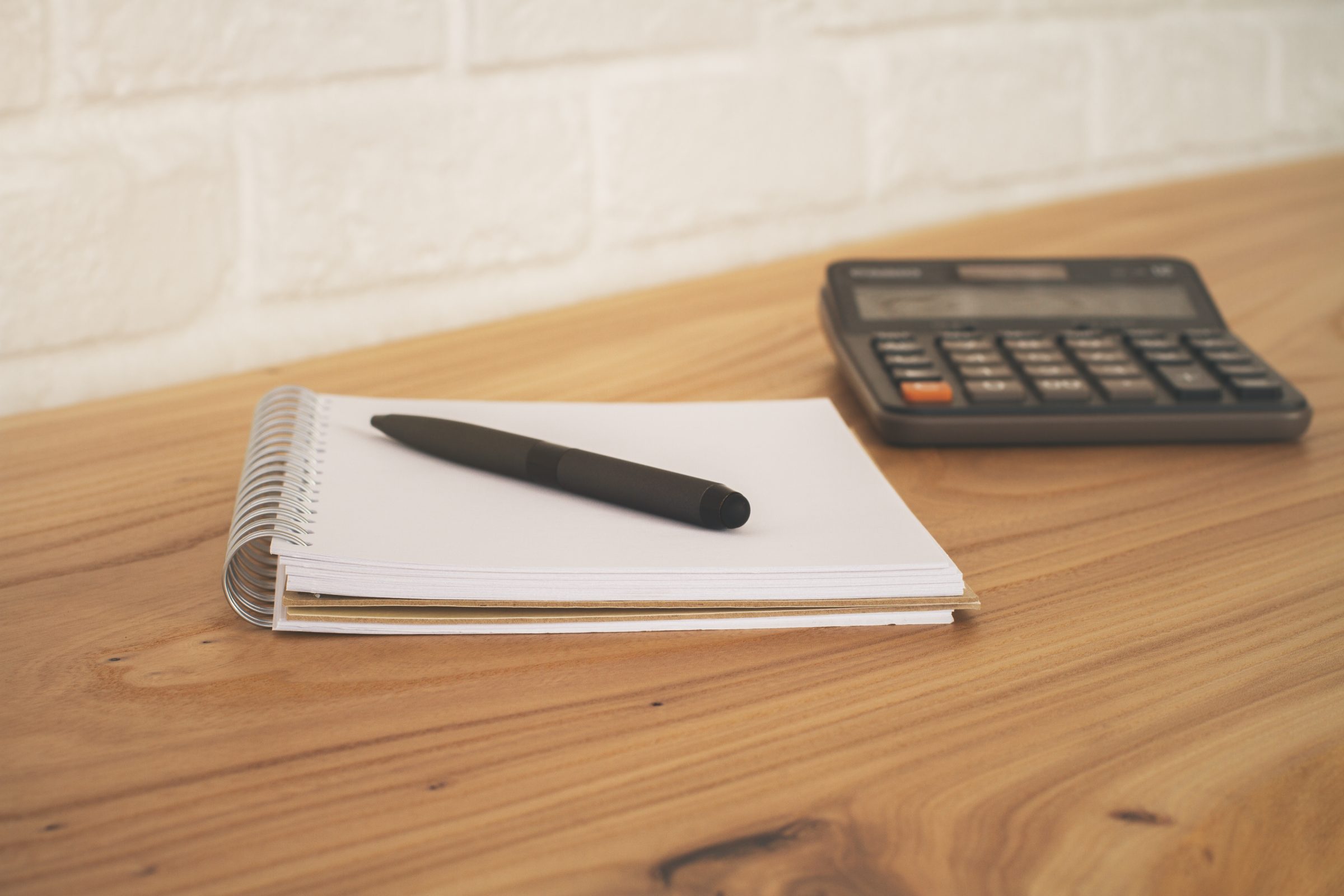 Notebook, pen and calculator on a wooden desk, for working out the cost of dental treatment